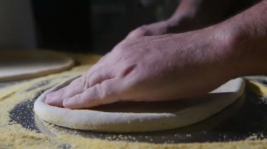 Erkek eller üzerinde sarı kraker slo-mo harika portre yayılan ve taze hamur pizza net kraker metalik bir tablo için döndürme Şef el ve yavaş bir mutfak yer pizza için taze hamur rulo