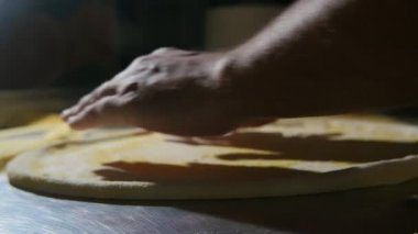 Şef eller slo-mo Arty closeup yayılan, iplik, değiştirme ve metalik bir tablo yavaş çekimde bir mutfakta pizza yemek için taze hamur yapma erkek el içinde bir tablo üzerinde bir pizza yapmak taze hamur yayılıyor
