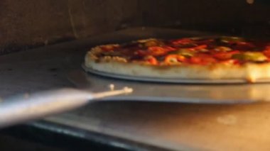 Lezzetli pizza salam, zeytin, domates, salam, kırmızı gravy, zeytin ve modern bir sıcak fırında metalik bir düz raket ile yerini peynir ile lezzetli pizza sıcak fırında portre onun konumunu değiştirme