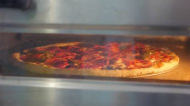İtalyan pizza domates, salam ve bir mutfak etkileyici closeup büyük bir pizza bir fırında pişirme zeytin ile dilim salam, peynir, zeytin, kırmızı domates sos ile kaplı. Bir mutfak modern fırında pişmiş