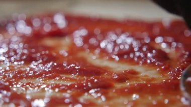 Erkek eli kırmızı makarna bir İtalyan pizza yemek için rulo pasta üzerine yayılan bir kaşıkla bir mutfak bir erkek el Closeup bir kaşıkla domates makarna rulo hamur üzerine yayılıyor. El yavaş yavaş hareket eder ve iyice çalışır. 