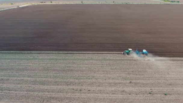 Vue aérienne d'un vaste champ agricole avec un tracteur qui le laboure en automne Vue aérienne impressionnante d'un tracteur qui sillonne un champ sans horizon et laisse derrière lui un nuage poussiéreux par une journée ensoleillée en automne 
