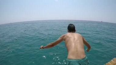 Sportif adam ellerini ilk denize atlama slo-mo üzerinde ve bir joung adam renkli şort eller ilk yaz yavaş hareket parlak yeşil deniz sularda dalış sualtı arkadan görünüm yaz aylarında bir iskeleden sular. 