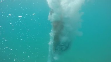 Ağır çekimde ayak ilk mavi deniz sularında onu ağır çekimde çevreleyen kabarcıklar çok hareketli bir gencin etkileyici atış aşağı genç adam hamlede transparan deniz suları balon patladı. Daha sonra o kadar yavaş yavaş yüzüyor.