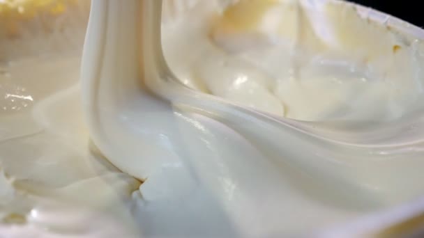 酸奶油采取了一个大勺子 混合和下降作为一个密集的流下来令人印象深刻的宏观拍摄密集的酸奶油混合和占去一个大的塑料勺子 它以螺旋的方式作为一条狭窄的小溪向下运球 — 图库视频影像
