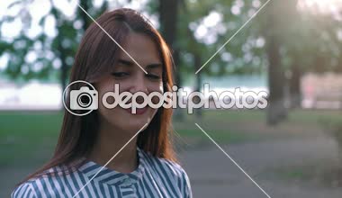 Ayakta ve yeşil bir sokakta neşeli oynak gözleri ve uzun bağsız kıl ayakta ve mutlu bir şekilde yaz aylarında yeşil bir parkta gülümseyen çizgili elbiseli olan komik bir kadın portresi yazında gülümseyen güzel esmer kız.