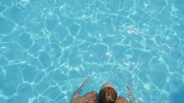 Sarışın kadın gülümseyerek, rahatlatıcı ve breasttroke ağır çekim sularda celeste ile yüzme havuzunda yüzme mavi bikinili sarışın bir gülümseyen kadın görünümünü aşağı slo-mo Splendid kürek çekmeye havuzda Sırtüstü yüzme istirahat