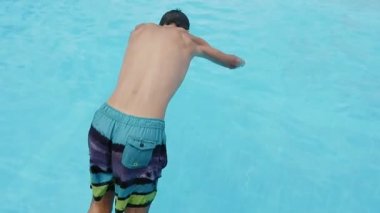 Genç adam kafa ilk yüzme havuz celestewater Genç, neşeli bir brunet adamın kafa ilk celeste deniz sularında yüzme gölet slo-mo yaz aylarında dalış renkli şortlu slo-mo harika görünümünde ile atlama rahatlatıcı