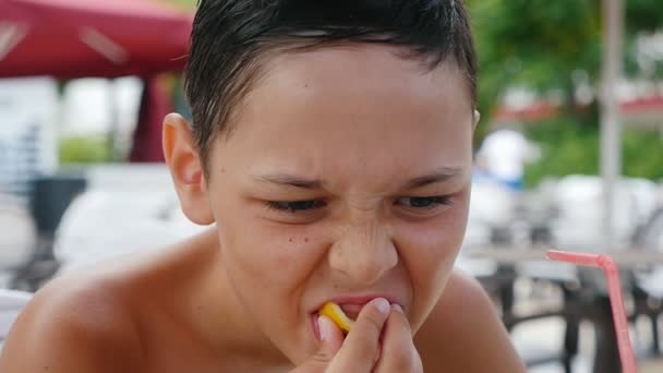 Piccolo Ragazzo Seduto Mangiare Una Fetta Limone Caffè Una Spiaggia — Video Stock