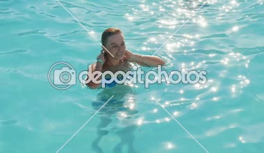 Celeste suları yüzme, eğlenceli ve yavaş hareket yaz aylarında suların parlayan ile wading bir havuzda sırada saçlarını koyarak mutlu bir sarışın kadının slo-mo Inspiring görünümünde bir yüzme havuzda neşeli sarışın kadın smartens.