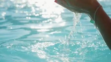 İki kadının elleri ile su havuzu güneş yoluyla slo-mo Inspiring görünümünde slo-mo Sunset'teki kristal turquiose suları ile açık havada bir seyyar havuz üzerinde parlayan su sıçramalarına yetiştirme iki eller üzerinde artış damla