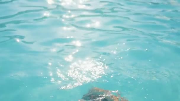 欢声色的女人俯冲下来 用慢动作的游泳工具闭上鼻子 令人激动的是 一个轻松的金发碧眼的女人在浅蓝色的水中移动 鼻子紧闭在游泳池里 慢动作的太阳路径 — 图库视频影像