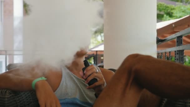 Hombre Divertido Extendiéndose Sillón Patio Aire Libre Vapeando Cigarrillo Electrónico — Vídeo de stock