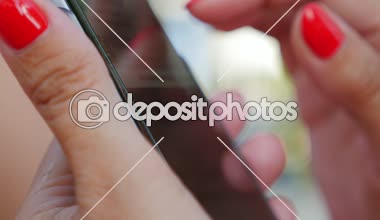 Zarif kadın kırmızı manikür bazı bilgi ve taze fotoğraflarla arayan bir smartphone net tarama ile bazı fotoğraflar şık ve bakımlı eller Closeup arayan bir smartphone cep telefonu ile internette sörf eller.