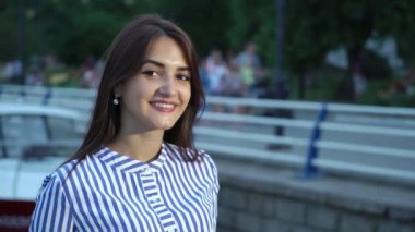 Mutlu neşeli bir brunet kadının yaz iyimser görünümünde akşam şık uzun bağsız kıl openheartedly yaz aylarında nehir iskele üzerinde gülümseyen bir zarif çizgili elbise ile bir nehir iskele üzerinde gülümseyen güzel genç kadın