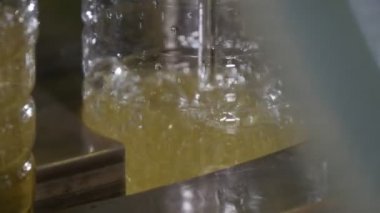 Petrol üretim tesisinde boş şişeler ve ayçiçeği yağı şişeleme doldurur. Şaşırtıcı closeup boş şişeler bir konveyör ayçiçek yağı üretimi için yenilikçi bitkinin üzerinde geçme içine akış ayçiçek yağı. 