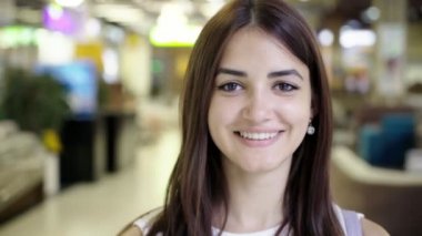 Mutlu yaz aylarında birçok bölümler ve ürünleri ile modern şehir alışveriş merkezinde gülümseyen uzun bağsız kıl ile neşeli bir genç brunet kadın portresi Ukrayna çeşitli bölümlerde dolu bir şehir alışveriş merkezinde gülümseyen mutlu genç kadın