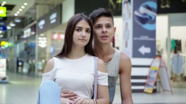 İnce kız ve erkek arkadaşı bir dükkan pencere varlık gözlemleyerek tamamen modern şehir alışveriş merkezinde şaşkınlık yeni moda giysiler ile bir dükkanı penceresine bakarak aşık genç bir aile duygusal görünümünü heyecanlı 