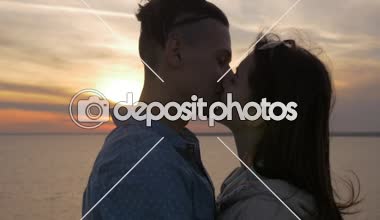 Tutkulu adam ihale kız arkadaşı slo-mo duygusal profili slo-mo yaz aylarında renkli batımında Karadeniz kıyısında uzun bağsız kıl aşık onun kız öpüşme aşık genç adam, güzel deniz batımında öpüşme