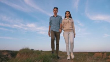 Neşeli brunet adam ve onun ince kız sahil bölümünde slo-mo muhteşem yaz slo-mo çimenli sahil üzerinde uzun bağsız kıl ile onun parlak brunet kızın elini tutarak aşık genç bir adam, olacak