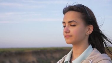 Glamour kız yavaş mavi bir manzarası ile bir kaba deniz plaj bağsız kıl ayakta slo-mo yaz aylarında akış ile güzel bir esmer kızın harika profil yaz aylarında mavi gökyüzü ile bir deniz kıyısında ayakta
