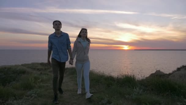 幸运的男人和他的好女儿在夏天去海边散步浪漫的景色 一对幸福的年轻夫妇在夏天的灿烂日落中走在黑海的草地海岸上 — 图库视频影像