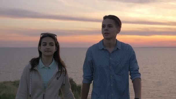 快乐的男人和他快乐的女孩在夏天走在海边的海滩上乐观乐观地看到 在夏天五颜六色的日落中 一对可爱的年轻夫妇一起在黑海的草地上散步 — 图库视频影像