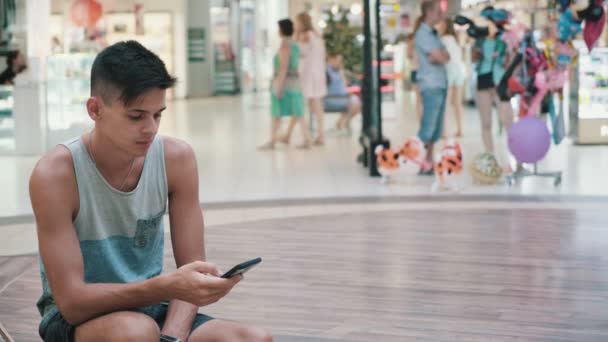 앉아서는 몰에서 전화에 인터넷 브라우징 반바지에 머리와 낚시를 좋아하는 젊은이의 — 비디오