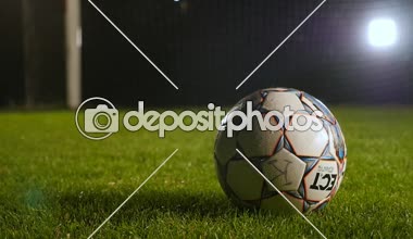 Futbol bir oyun alanı üzerinde yalan ile çivili bir spor ayakkabı slo-mo Amazing görünümünde bir çim üzerinde yalan bir futbol bacağından vurmak ve bir çivili spor ayakkabı mesafesinde ve yavaş hareket başladı