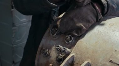 Tek tip bir vida somun ile büyük bir İngiliz anahtarı üzerinde küresel jeneratör bir üniforma ve büyük bir İngiliz anahtarı üzerinde bir jeneratör ile bir fındık dönüm eldiven bir işçi Close-up dönüm işçi