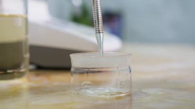 Şeffaf sıvı kristal düşme kimyasal laboratuvar etkileyici görünümünde bir ölçek bir pipet üzerinden bırakarak bir laboratuvarda bir tıp Cam Pipet üzerinden düşen damlaları