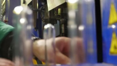 Bitki üzerinde binme konveyör yüklü uzun cam şişeler etkileyici görünümü üreten bir petrol üzerinde hareketli bir konveyör cam bulbes koyarak alt yeşil üniformalı bir işçi tarafından