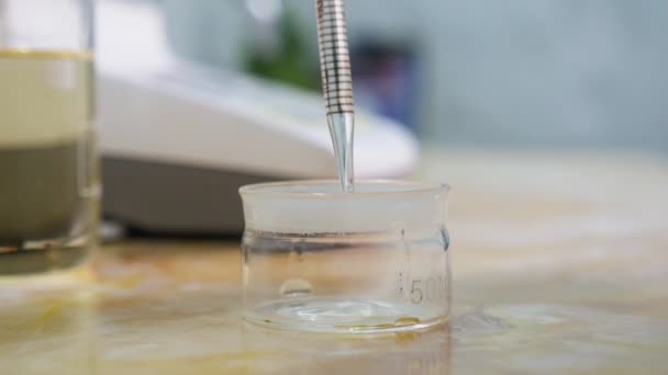 在化学实验室的烧杯中 透明液体从移液器中滴下来令人印象深刻的是 在实验室的药杯中 下降的晶体掉落会从移液器中坠落 — 图库视频影像