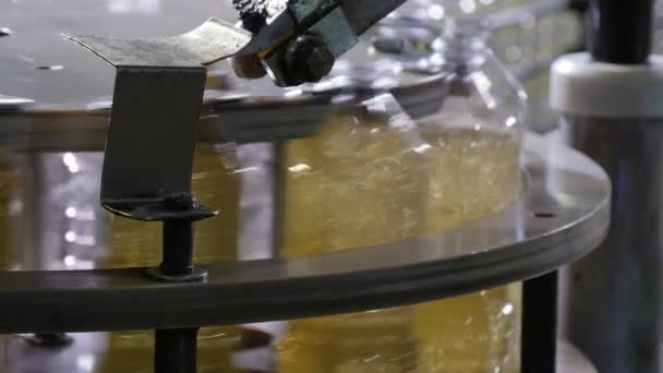 黄色的油溅在透明的瓶子里 通过工厂的金属喷嘴 在缓慢运动的情况下 看到油洒在传送带上的塑料瓶里 — 图库视频影像