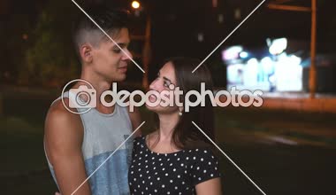 Mutlu çocuk ve City yaz sohbet ve yaz aylarında bir sokakta gülümseyen bir gri gömlek bir sarılma çekici kızla uzun bağsız kıl, mutlu bir brunet adam romantik bakış gece sokak sohbet gülümseyen bal kız
