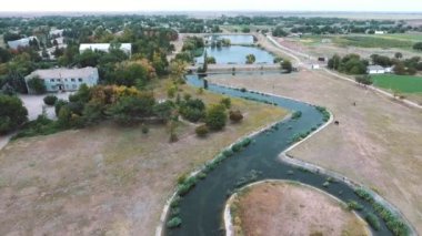 Bükülmüş bir kanal ile yaz aylarında Ukrayna yapraklı ağaçların arkasında görülen iki kare göl uzanan bir küçük adacık ile yaz sanat konusunda hava atan kuş bakışı snaky bir kanal içinde iki göl için çalışan bir küçük adacık havadan çekim