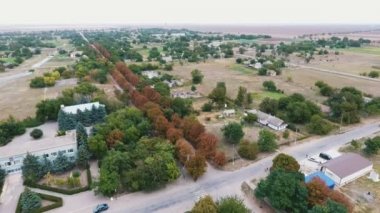 Bir kavşak ve yaz Amazing kuş bakışı çizgili kahverengi ve yeşil ağaçların iki geçiş yolları boyunca yaz aylarında yerleştirilen mutistoried beyaz binaların içinde ağaçların hatları ile bir yerleşimin hava atış