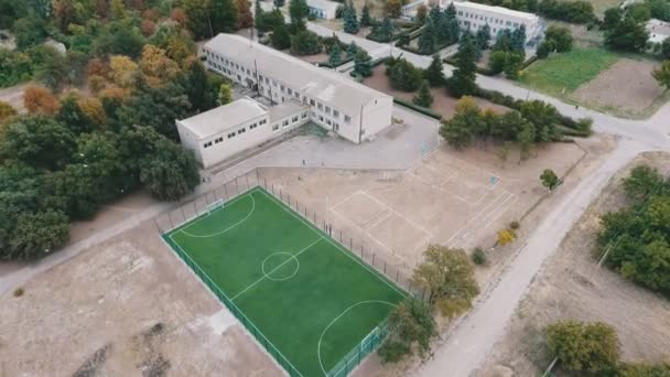 階建ての建物近くにウクライナの夏に現代緑のサッカー フィールドの夏素敵な鳥の目のビューの建物と手入れのフットボール競技場の空中ショット — ストック動画