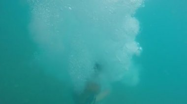 Genç brunet dostum dalış ayak ilk sualtı slo-mo uzun bir sportif brunet erkekte özgün sualtı görünümüne çok kabarcıklar ile düşen ayak ilk Türkiye'de deniz dibine yavaş yaz aylarında şort