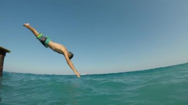 Sportif adam ayakta ve yüksek baş ilk sportif bir gencin uzun şort kafa önce Türkiye'de mavi deniz sularında yavaş yaz aylarında güzel gün atlama slo-mo profilde Türkiye'de açık denize atlama