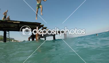 Ayakta ve ayak ilk sportif bir gencin uzun şort ayak ilk yavaş yaz aylarında güneşli bir günde celste deniz sularında dalış slo-mo neşeli görünümünde dalgalar deniz Türkiye'de atlama brunet delikanlı