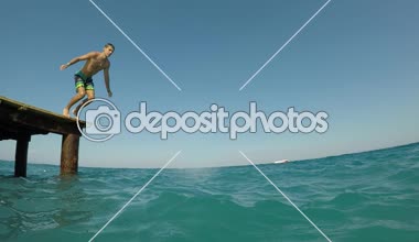 Ayakta ve kafa önce slo-mo sportif bir gencin uzun şort celeste deniz suları Türkiye'de kafasından ağır çekimde yaz aylarında güneşli günde atlama iyimser görünümü Türkiye'de açık denize atlama brunet delikanlı