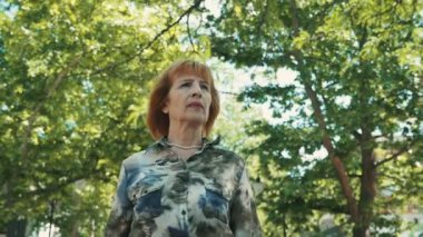 Kendine güvenen kadın kıdemli yeşil bir parkta yavaş yaz aylarında aşağı başarılı bir üst düzey kadın görünümünü kadar şık bir çok renkli bluz yavaş yaz yeşil bir sokakta gidiş içinde bob saç kesimi ile yürüyüş,