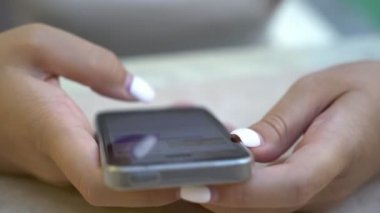 Kadının beyaz manikür hızlı bir smartphone bir kafeteryada yazarak ile güzel eller özgün closeup ile net sörf ve hızlı bir şekilde güzel bir kafeterya onun parlayan smartphone yazarak beyaz manikür eller.