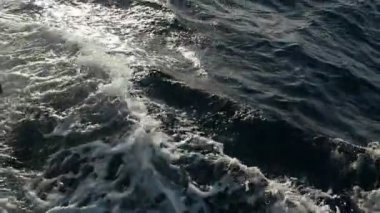 Beyaz köpüklü dalgalar üzerinde koyu mavi dalgalar köpüklü damla ve ağır çekimde görkemli günbatımında bir turistik gemi yayından dashing boncuk dolu sıçramasına slo-mo çarpıcı görünümü güneşli bir günde bir turistik gemi yayından acele.