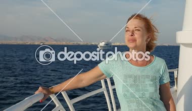 Sarışın kadın ayakta gemi tırabzan Sharm El Sheikh bir gülümseyen, slo-mo neşeli görünümünde, sarışın kadın bir Tshirt giyinmiş ve bir korkuluk güneşli günde Mısır'da çekimde eğilerek turistik bir gemide seyahat ilham