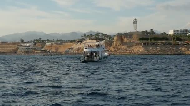 スローモーション スローモーションで晴れた日にエジプトのシャルム シェイクの時海海岸へ移動大きな近代的な観光船の素晴らしい景色で丘陵海辺でシャルム シェイクで水上大きな観光船 — ストック動画