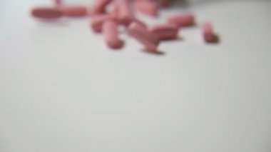 Vitamini pastilleri, oynayan beyaz iplik ve haddeleme haddeleme ve slo-mo beyaz stüdyo masada oynarken pembe hap slo-mo neşeli makro kadeh tabloda. Sağlık ve Eğlence havasında ürettikleri.