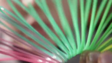 Makro çekim plastik gökkuşağı sinsi bobinleri neşe, iyimserlik ağır çekimde ruhu üreten şekillendirdiği bir curvy çok renkli Boru Plastik gökkuşağı sinsi bobinleri ağır çekimde Curvy renkli tüp oluşturduğu