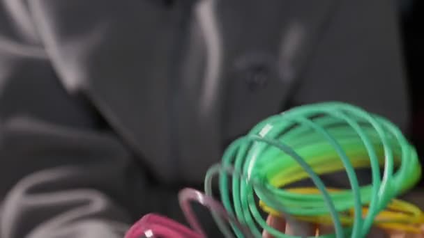 Garçon inspiré jouant et déplaçant les bobines slinky arc-en-ciel au ralenti Plan macro d'un petit garçon jouant joyeusement avec un arc-en-ciel en plastique multicolore slinky et faisant diverses figures dans une pièce au ralenti .